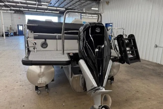 Slide: The Image of 2025 Harris Sunliner 230 pontoon boat with sleek black motor in a spacious indoor setting. - 7