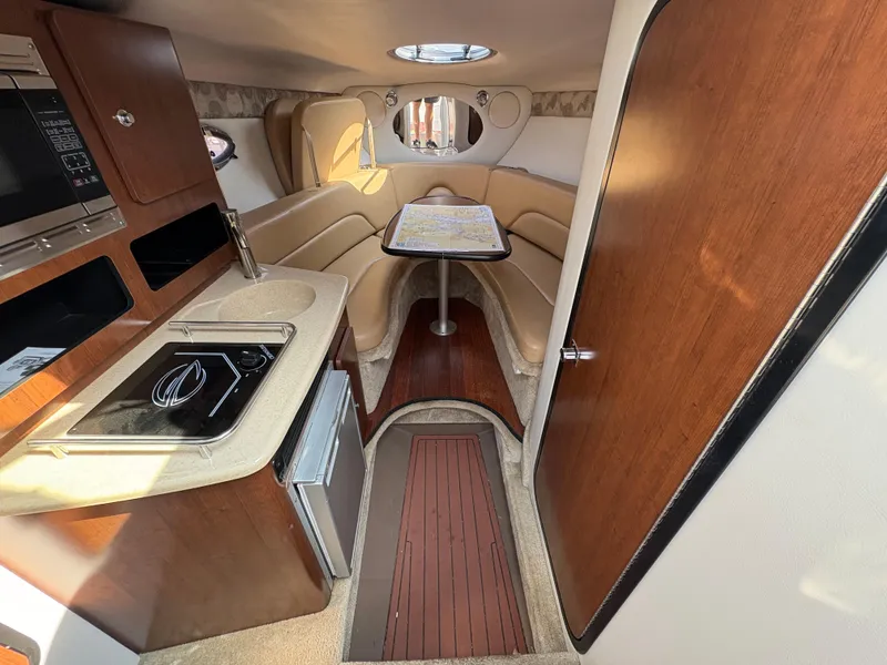 Slide: The Image of 2019 Crownline 264 CR cabin interior with kitchenette, seating area, and wooden finishes. - 11