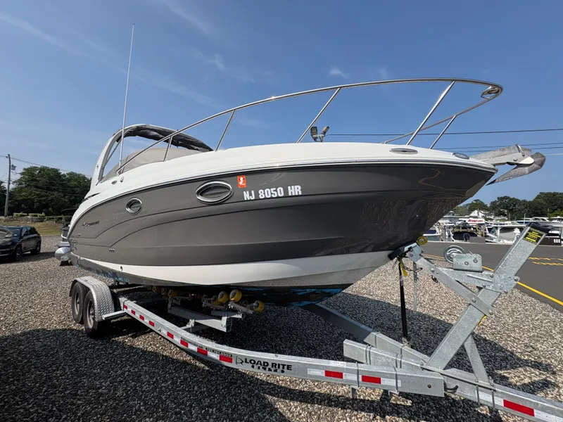 Slide: The Image of 2019 Crownline 264 CR boat on trailer, parked outdoors under clear sky. - 2