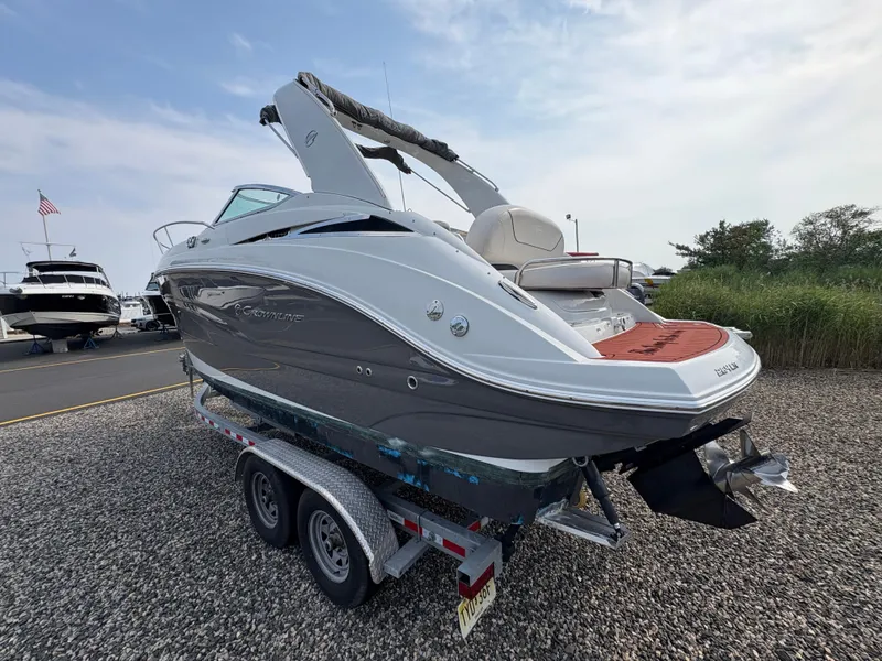 Slide: The Image of 2019 Crownline 264 CR boat on trailer, parked on gravel, with clear sky background. - 4