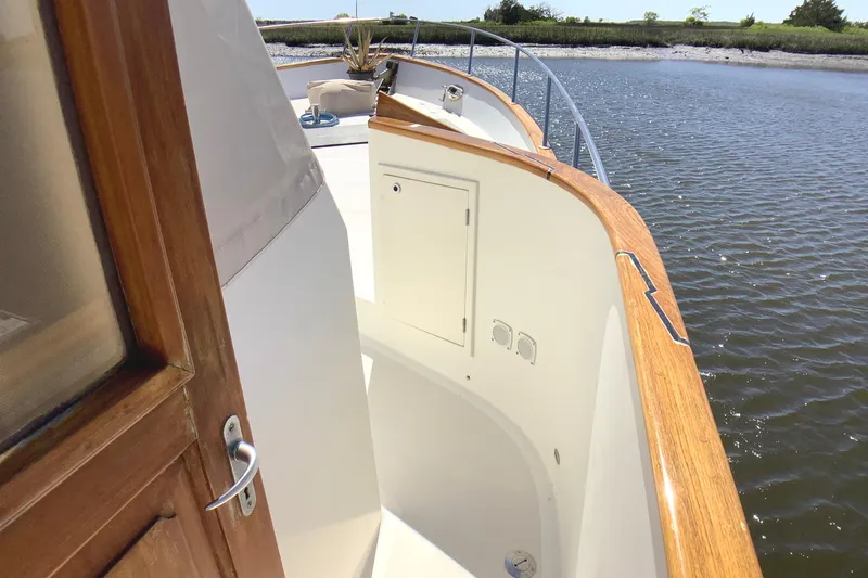 Slide: The Image of 1998 Grand Alaskan 60 Pilothouse yacht deck with wooden railings and water view. - 10