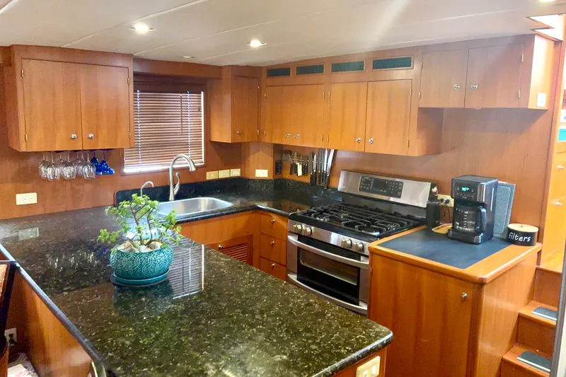 Slide: The Image of Luxurious kitchen in 1998 Grand Alaskan 60 Pilothouse yacht with granite countertops and wooden cabinetry. - 16