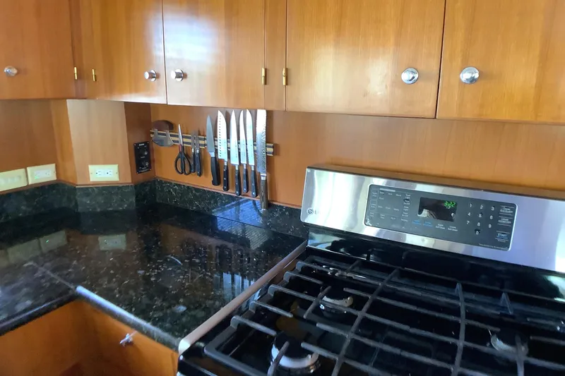 Slide: The Image of Kitchen in 1998 Grand Alaskan 60 Pilothouse with granite countertops and stainless steel stove. - 19