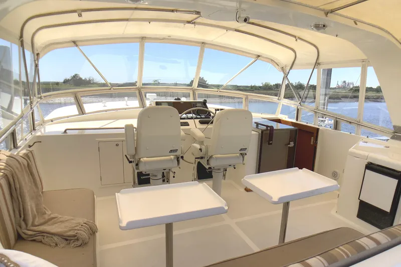 Slide: The Image of Luxurious 1998 Grand Alaskan 60 Pilothouse interior with seating and helm, overlooking serene waters. - 38