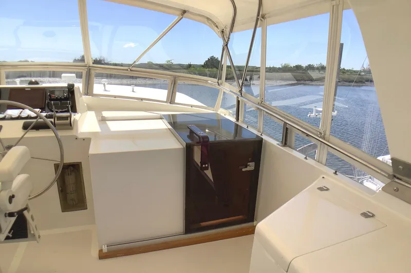 Slide: The Image of 1998 Grand Alaskan 60 Pilothouse interior with steering wheel, windows, and water view. - 46