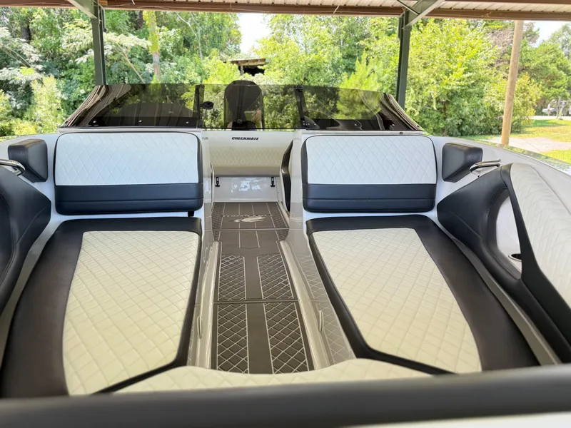 Slide: The Image of 2024 Checkmate Pulsare 2400 BRX boat interior with white and black seating under a canopy. - 18