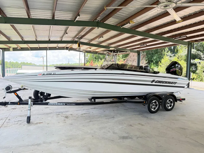 Slide: The Image of 2024 Checkmate Pulsare 2400 BRX boat on trailer under metal roof. - 2