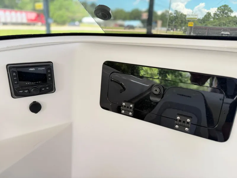 Slide: The Image of 2024 Checkmate Pulsare 2400 BRX boat interior with audio system and storage compartment. - 22