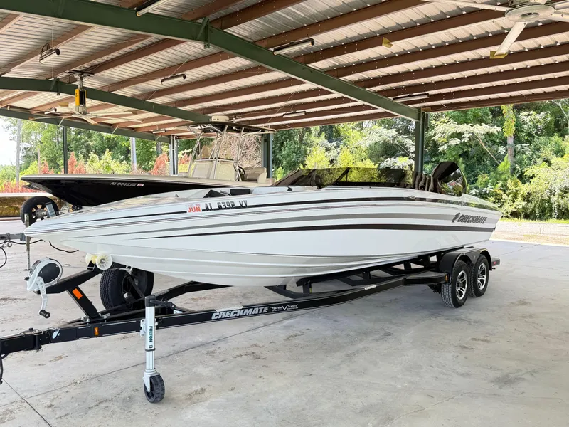 Slide: The Image of 2024 Checkmate Pulsare 2400 BRX boat on trailer under a metal canopy. - 3