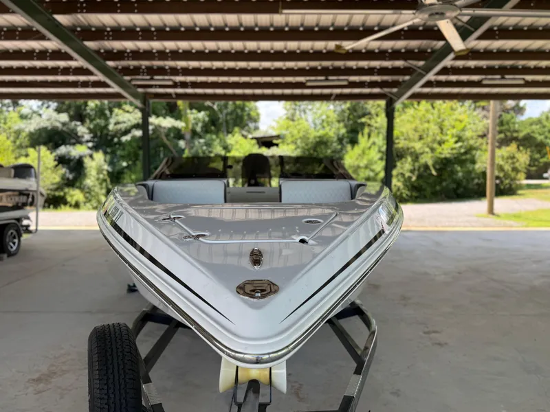 Slide: The Image of 2024 Checkmate Pulsare 2400 BRX boat on trailer under a metal canopy. - 4