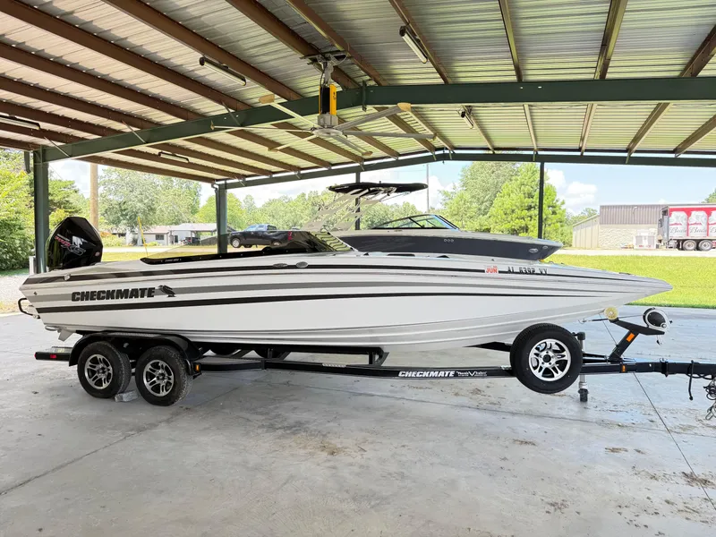 Slide: The Image of 2024 Checkmate Pulsare 2400 BRX boat on trailer under a metal canopy. - 6