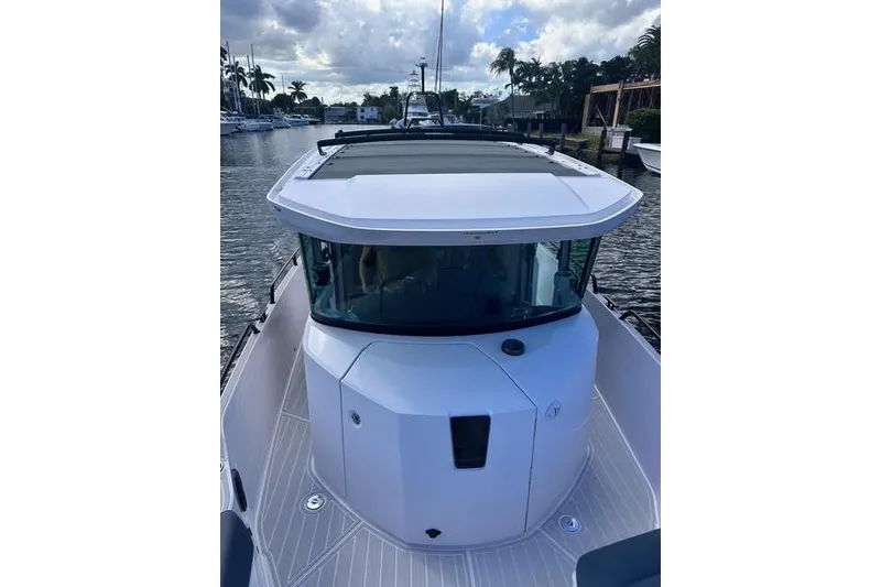 Slide: The Image of 2023 Axopar 28 CABIN boat docked on a calm waterway under a cloudy sky. - 12
