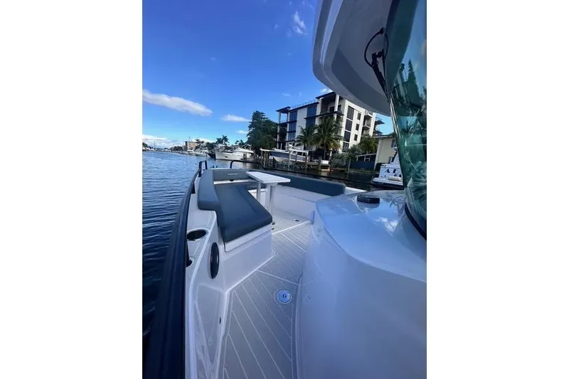 Slide: The Image of 2023 Axopar 28 CABIN boat docked near waterfront buildings under blue sky. - 13
