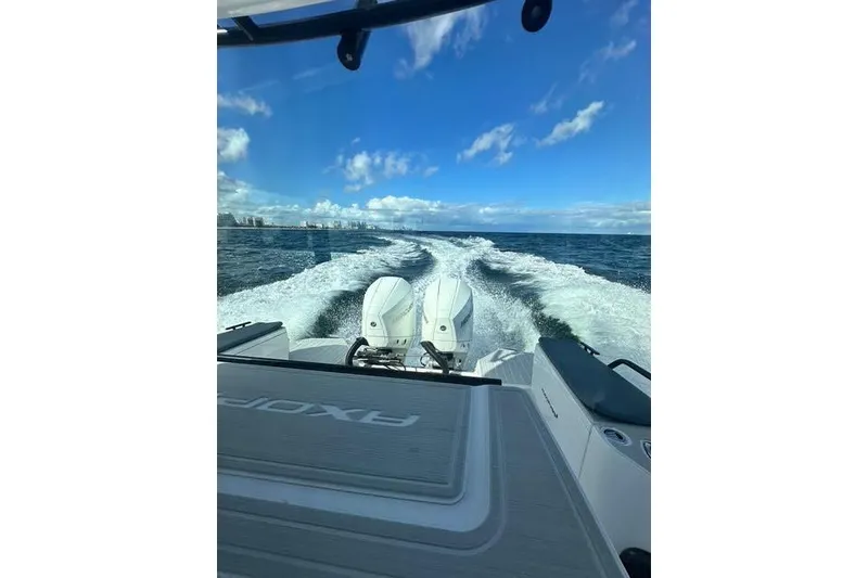 Slide: The Image of 2023 Axopar 28 CABIN boat cruising on open water under a clear blue sky. - 16