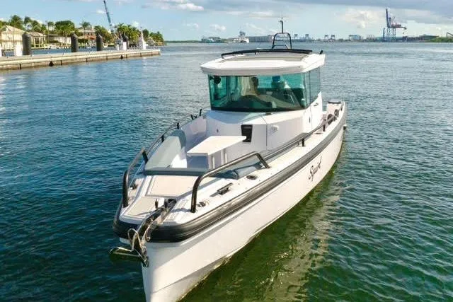 Slide: The Image of 2023 Axopar 28 CABIN boat cruising on a sunny day in a scenic harbor. - 6