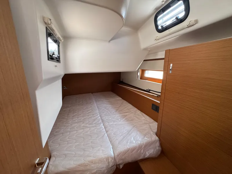 Slide: The Image of 2024 Beneteau First 44 cabin interior with bed, wooden finish, and portholes. - 12
