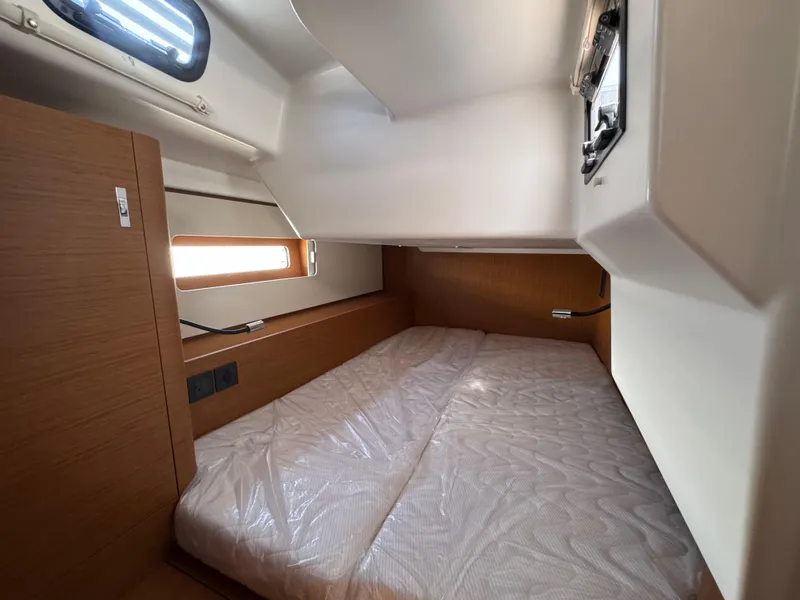Slide: The Image of 2024 Beneteau First 44 cabin interior with bed, wooden accents, and natural light. - 13