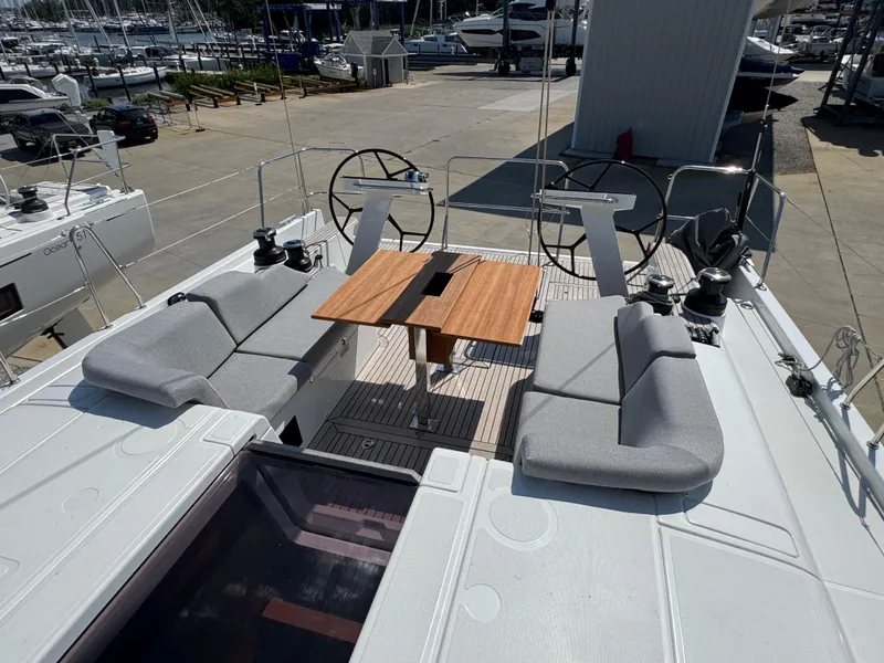 Slide: The Image of 2024 Beneteau First 44 yacht deck with dual steering wheels and seating area. - 2