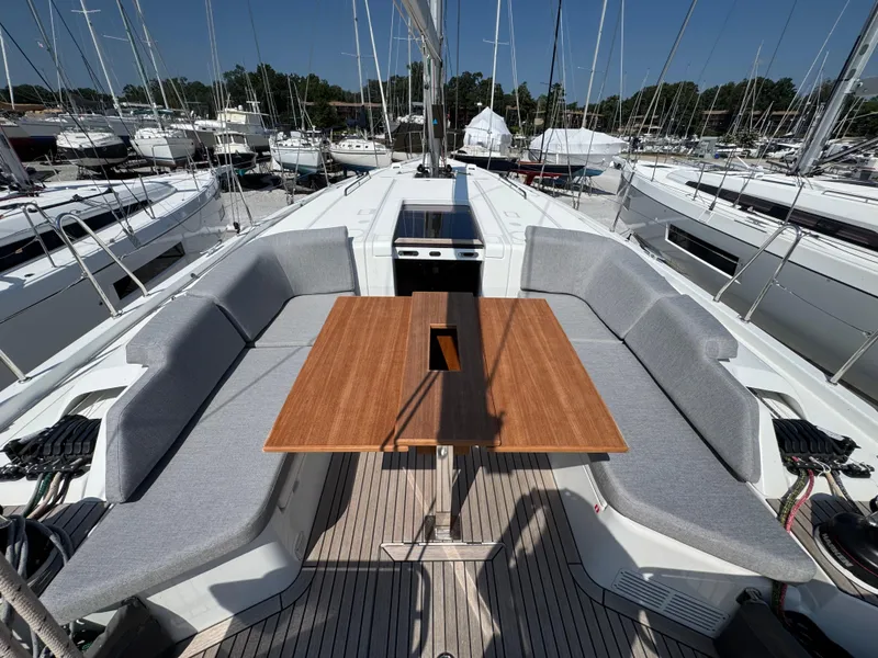 Slide: The Image of 2024 Beneteau First 44 yacht cockpit with wooden table and cushioned seating. - 6