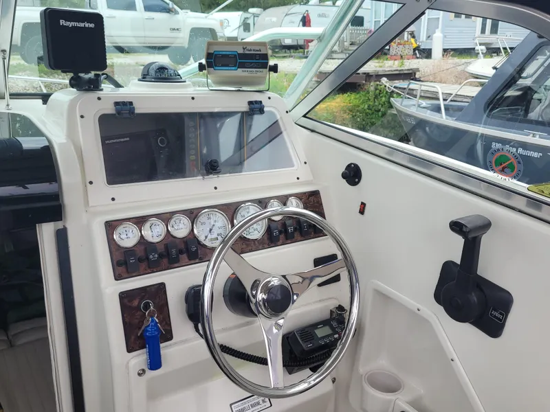 Slide: The Image of 2003 Caravelle Sea Hawk 230 Walk Around OB boat dashboard with steering wheel and navigation instruments. - 10