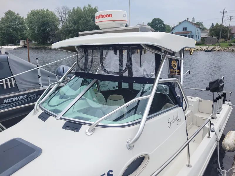 Slide: The Image of 2003 Caravelle Sea Hawk 230 Walk Around OB boat docked by the water. - 2