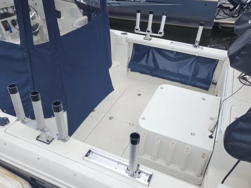 Slide: The Image of 2003 Caravelle Sea Hawk 230 Walk Around OB boat interior with rod holders and seating. - 8