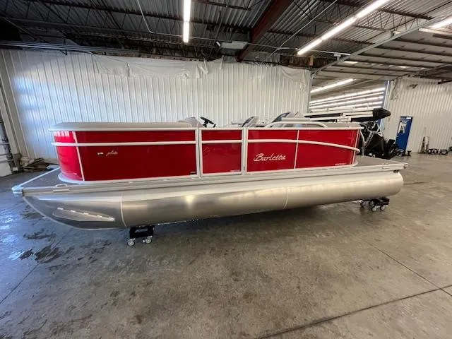 Slide: The Image of 2025 Barletta ARIA 20QC pontoon boat in a warehouse, featuring a sleek red design. - 2