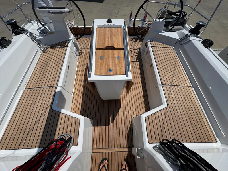 Slide: The Image of 2025 Beneteau Oceanis 40.1 yacht cockpit with teak flooring and dual steering wheels. - 2