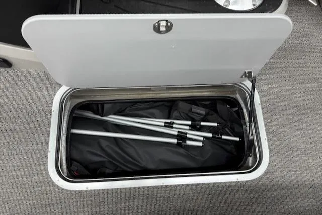 Slide: The Image of Storage compartment in 2025 Barletta Cabrio 22QC boat, containing folded metal poles. - 14