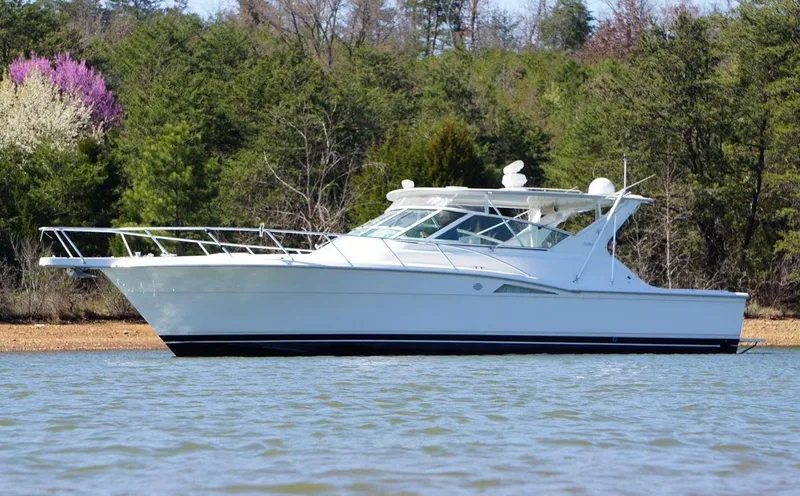 The Image of 1998 Hatteras 39 Sport Express boat on calm water, surrounded by lush greenery. - 0