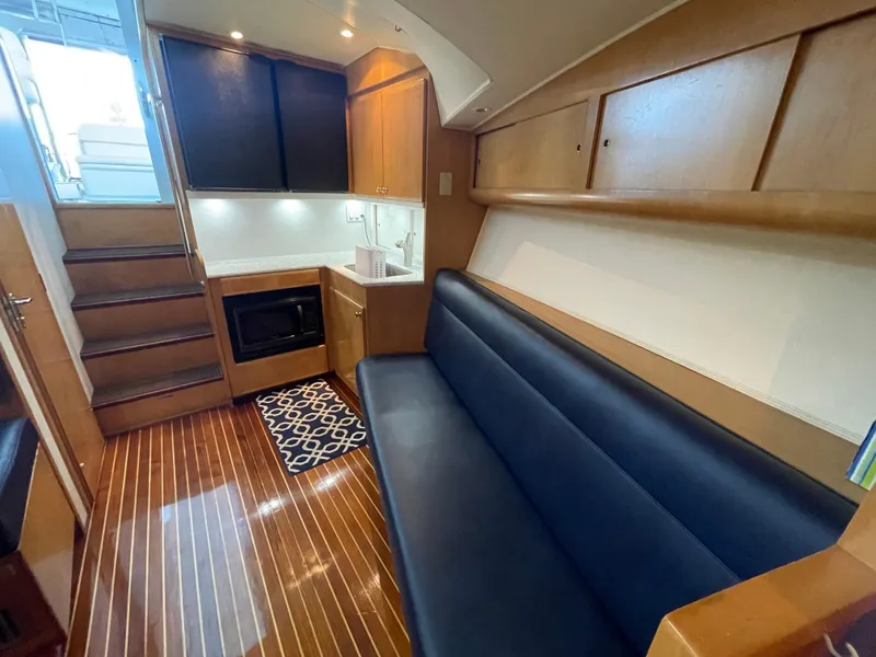Slide: The Image of Interior of 1998 Hatteras 39 Sport Express with wooden flooring and blue seating. - 26