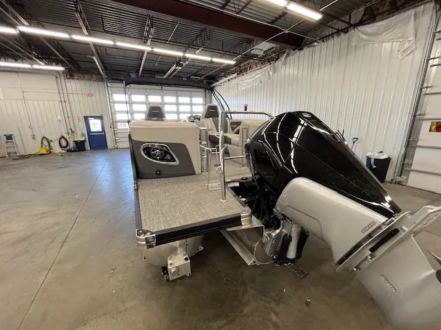 Slide: The Image of 2025 Barletta CORSA 23QC pontoon boat in a warehouse, featuring a powerful outboard motor. - 26