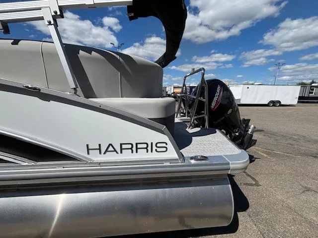 Slide: The Image of 2025 Harris Cruiser 230 pontoon boat with Mercury outboard motor, parked under a blue sky. - 5