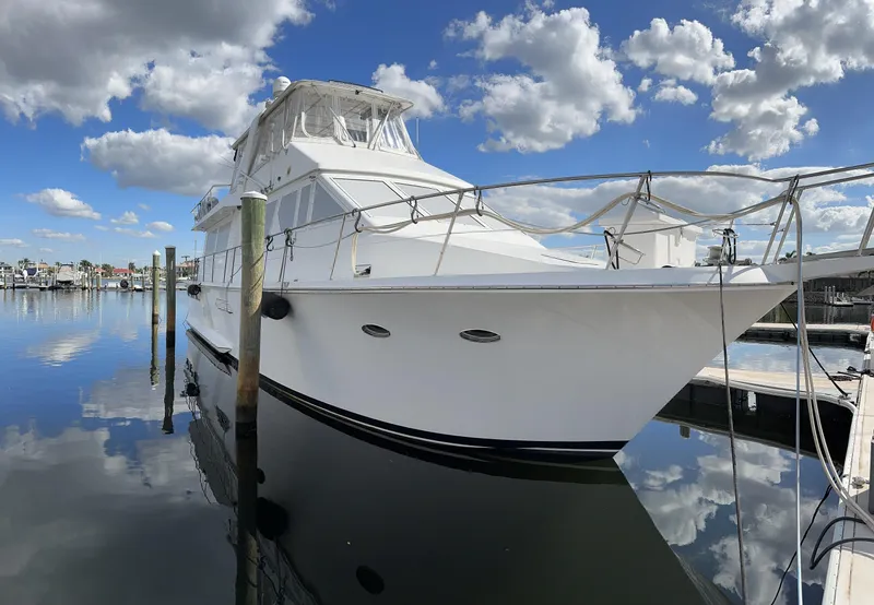 Slide: The Image of 1988 Viking Motor Yacht docked at a marina under a blue sky with clouds. - 1