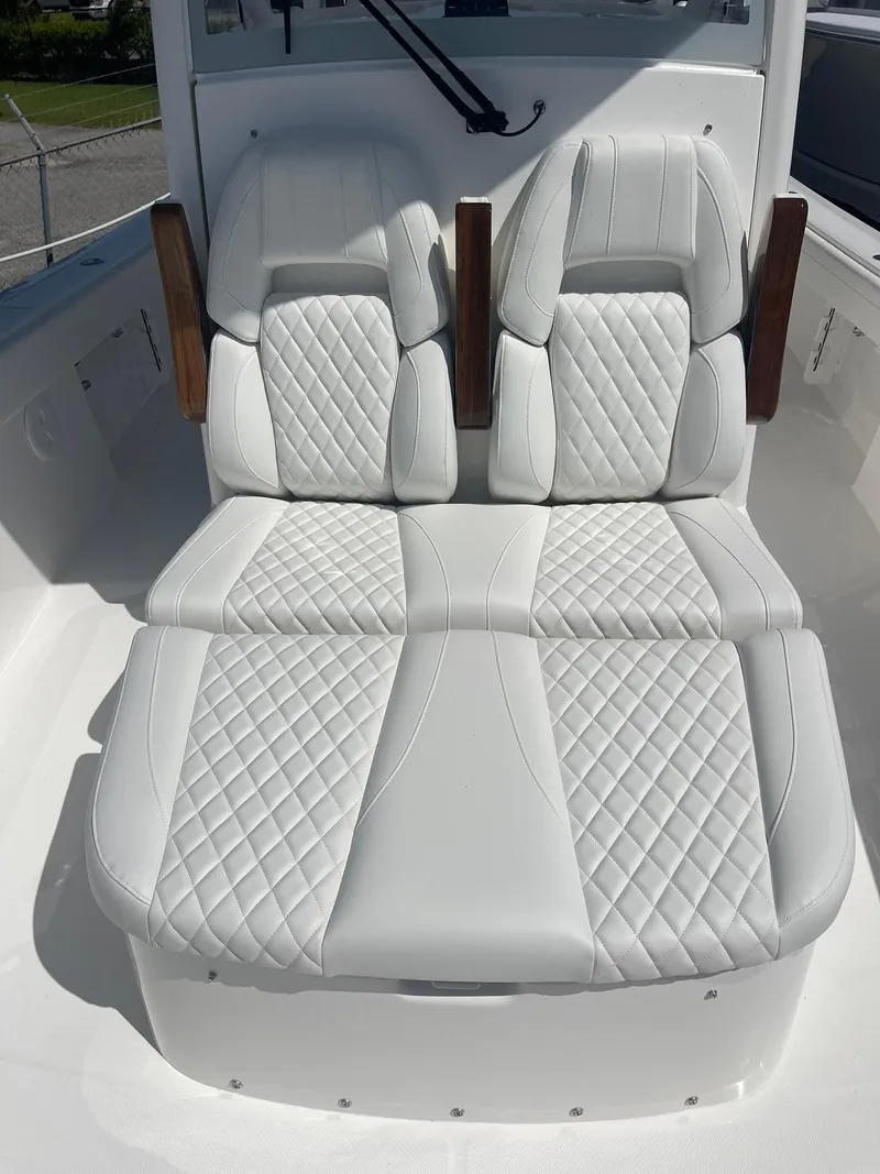 Slide: The Image of Luxurious white seating on 2026 Regulator 30XO boat, featuring diamond stitching and wooden armrests. - 13