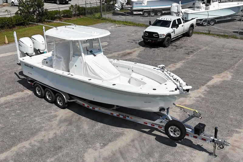 Slide: The Image of 2026 Regulator 30XO boat on trailer, parked in a lot with a truck nearby. - 19