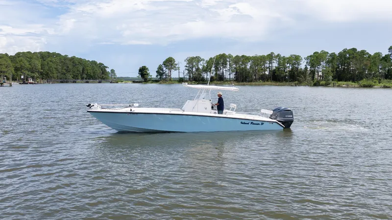 Slide: The Image of 1999 Island Runner 31 boat cruising on a calm lake with trees in the background. - 10