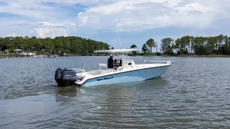Slide: The Image of 1999 Island Runner 31 boat on calm water with trees in the background. - 12