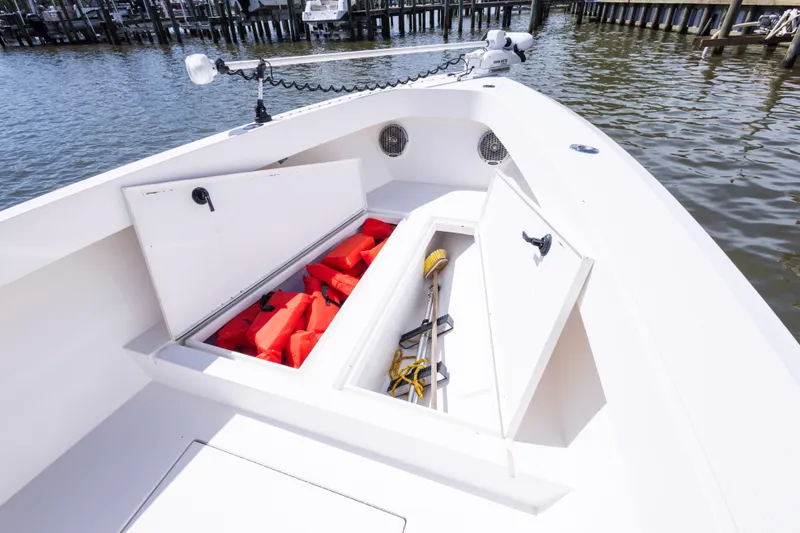 Slide: The Image of Open storage compartments on a 1999 Island Runner 31 boat, containing life jackets and cleaning tools. - 31