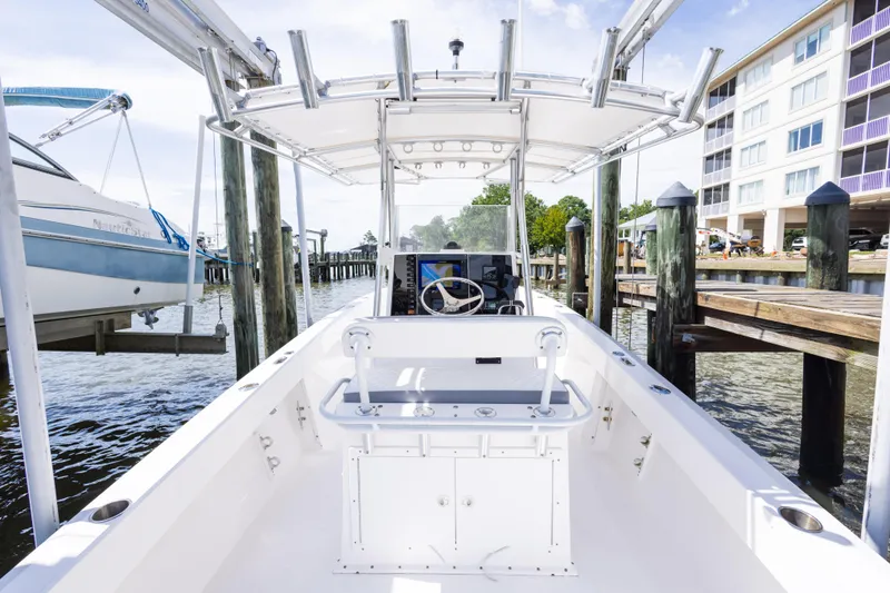 Slide: The Image of 1999 Island Runner 31 boat docked, featuring a center console and T-top, near waterfront buildings. - 32