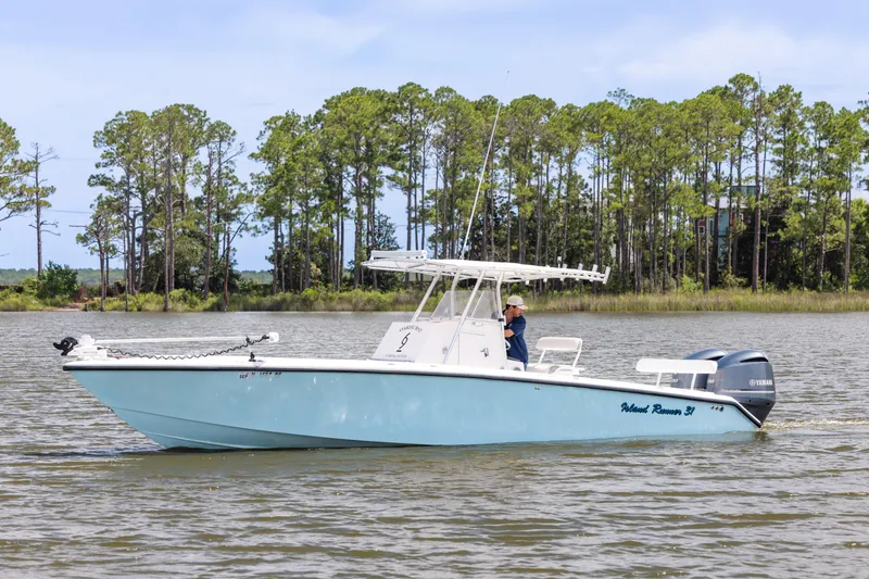 Slide: The Image of 1999 Island Runner 31 boat on a calm lake with trees in the background. - 4