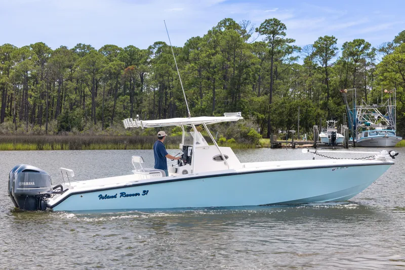 Slide: The Image of 1999 Island Runner 31 boat on water, with Yamaha engines, surrounded by trees and docks. - 5