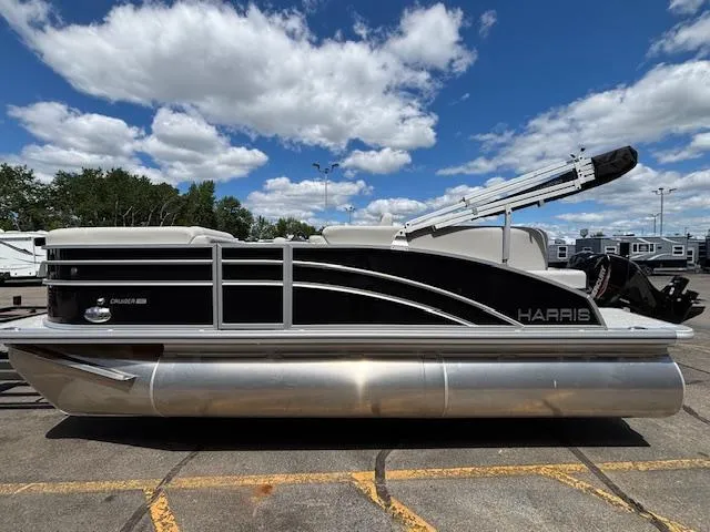 Slide: The Image of 2025 Harris Cruiser 190 pontoon boat parked under a partly cloudy sky. - 2
