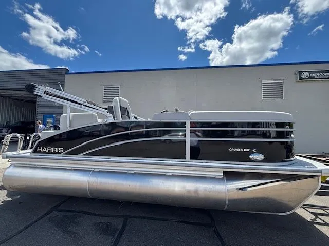 Slide: The Image of 2025 Harris Cruiser 190 pontoon boat parked outdoors under a blue sky. - 3