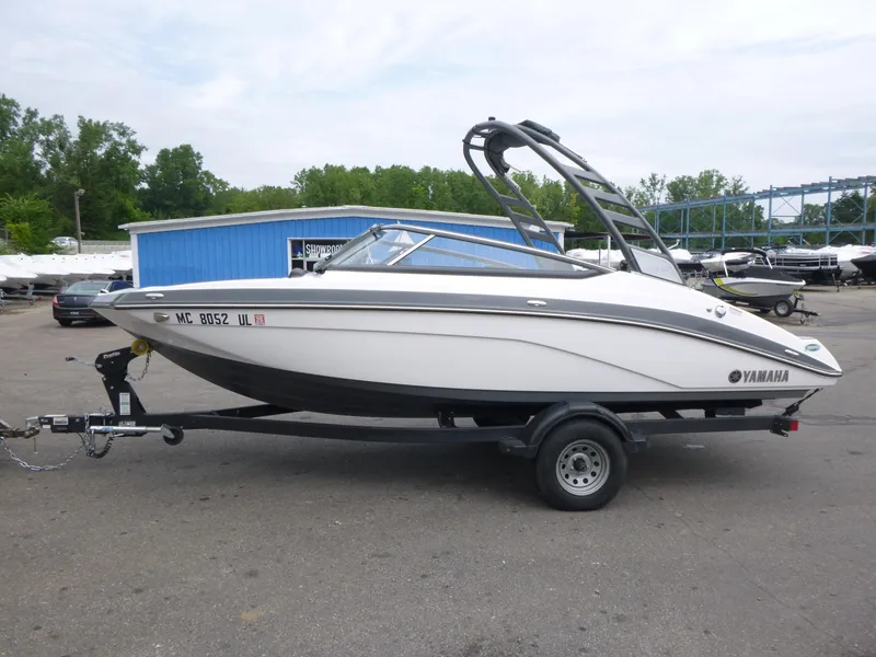 Slide: The Image of 2020 Yamaha Boats 195S on trailer, parked outdoors near blue building. - 1