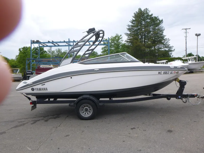 Slide: The Image of 2020 Yamaha Boats 195S on trailer, parked outdoors with trees in background. - 2