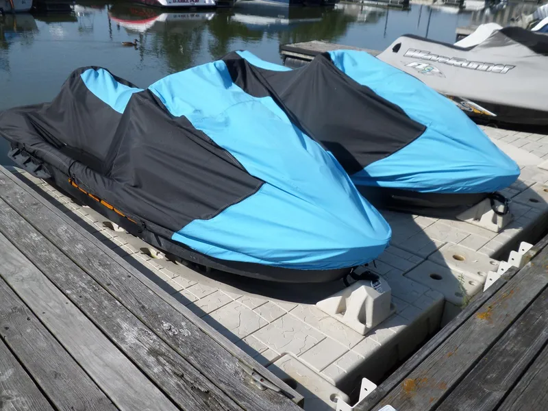 Slide: The Image of Two covered 2021 Sea-Doo GTI SE 170 jet skis docked on a sunny day. - 2