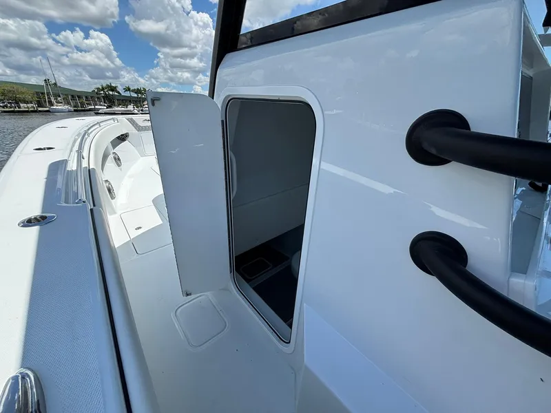 Slide: The Image of 2026 Invincible 36 Open Fisherman boat with open storage compartment, docked under a cloudy sky. - 18