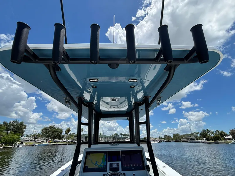 Slide: The Image of 2026 Invincible 36 Open Fisherman boat with rod holders and navigation system under a blue sky. - 28