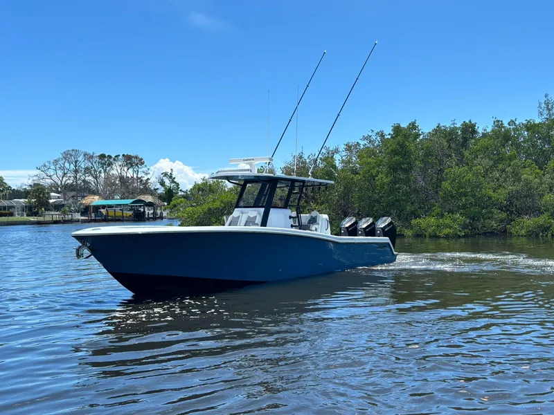 Slide: The Image of 2026 Invincible 36 Open Fisherman boat cruising on a sunny day near lush greenery. - 5